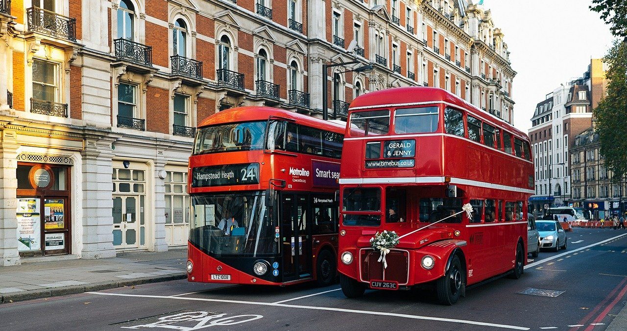 An old London bus next to a new bus